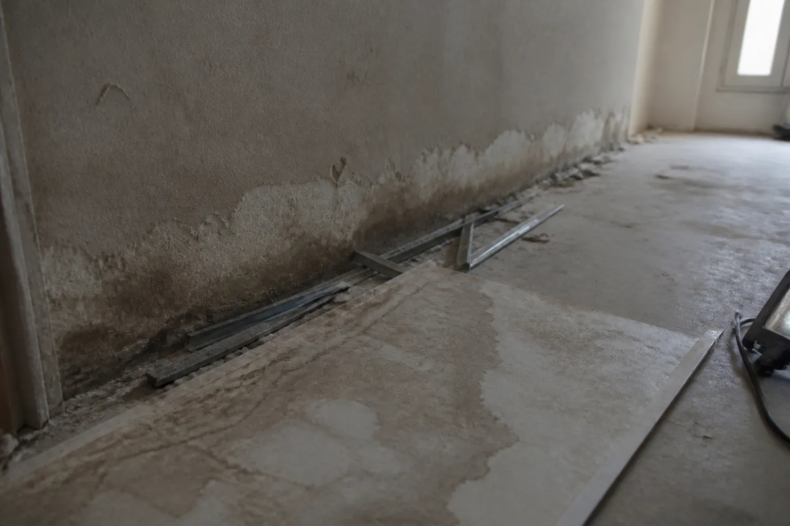 Trace d’humidité en bas de cloison après dépose du doublage, revers du panneau isolant et mur de maçonnerie apparent derrière